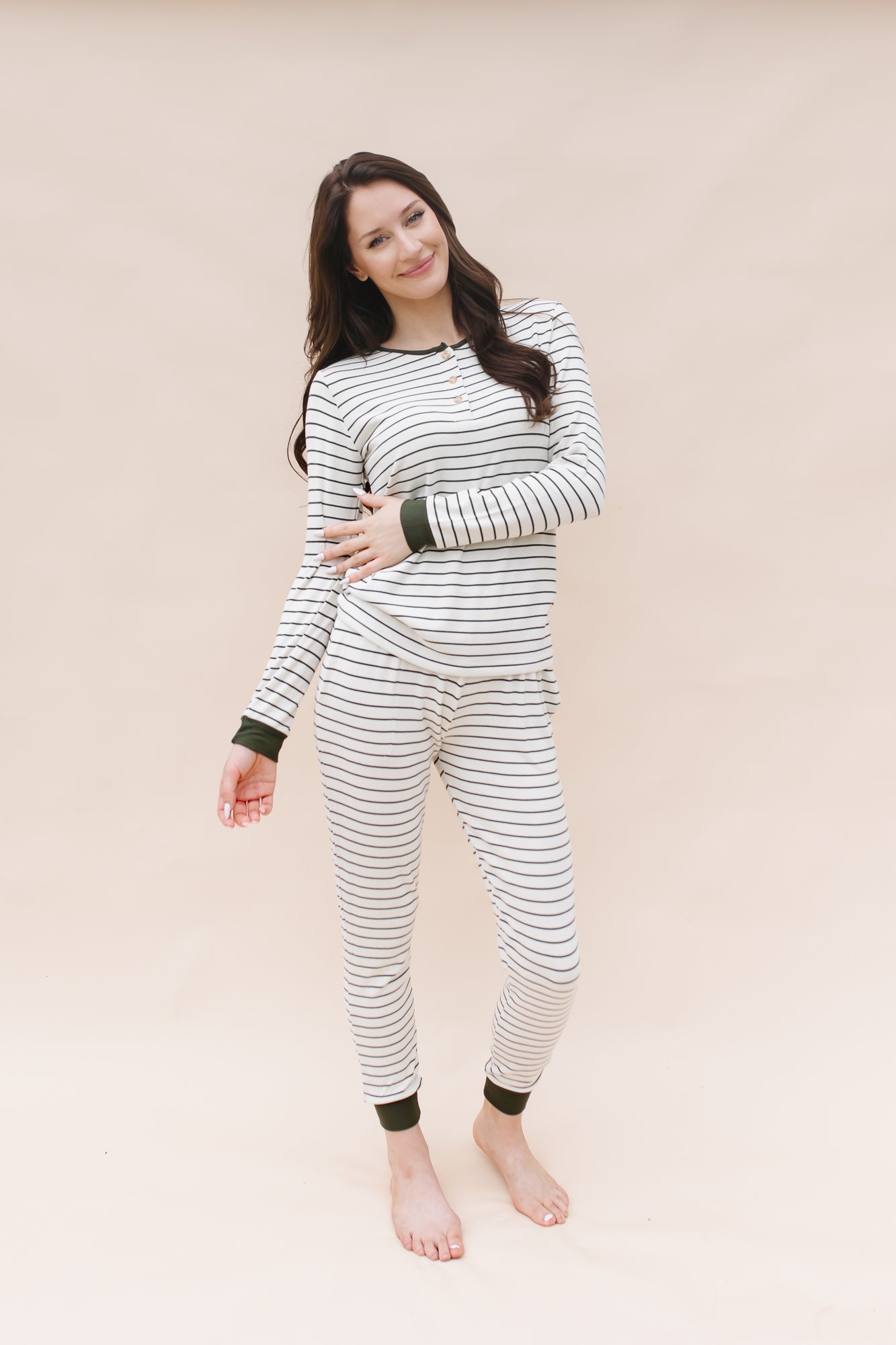 Model with one arm across body while wearing the Kyte Women’s Ribbed Henley Set in Fir Stripe