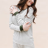 Model looking to the side while hugging herself while wearing the Kyte Women’s Ribbed Henley Set in Fir Stripe