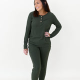 Female model standing with one hand on her hip wearing the Women’s Ribbed Henley Set in Fir in front of a white backdrop