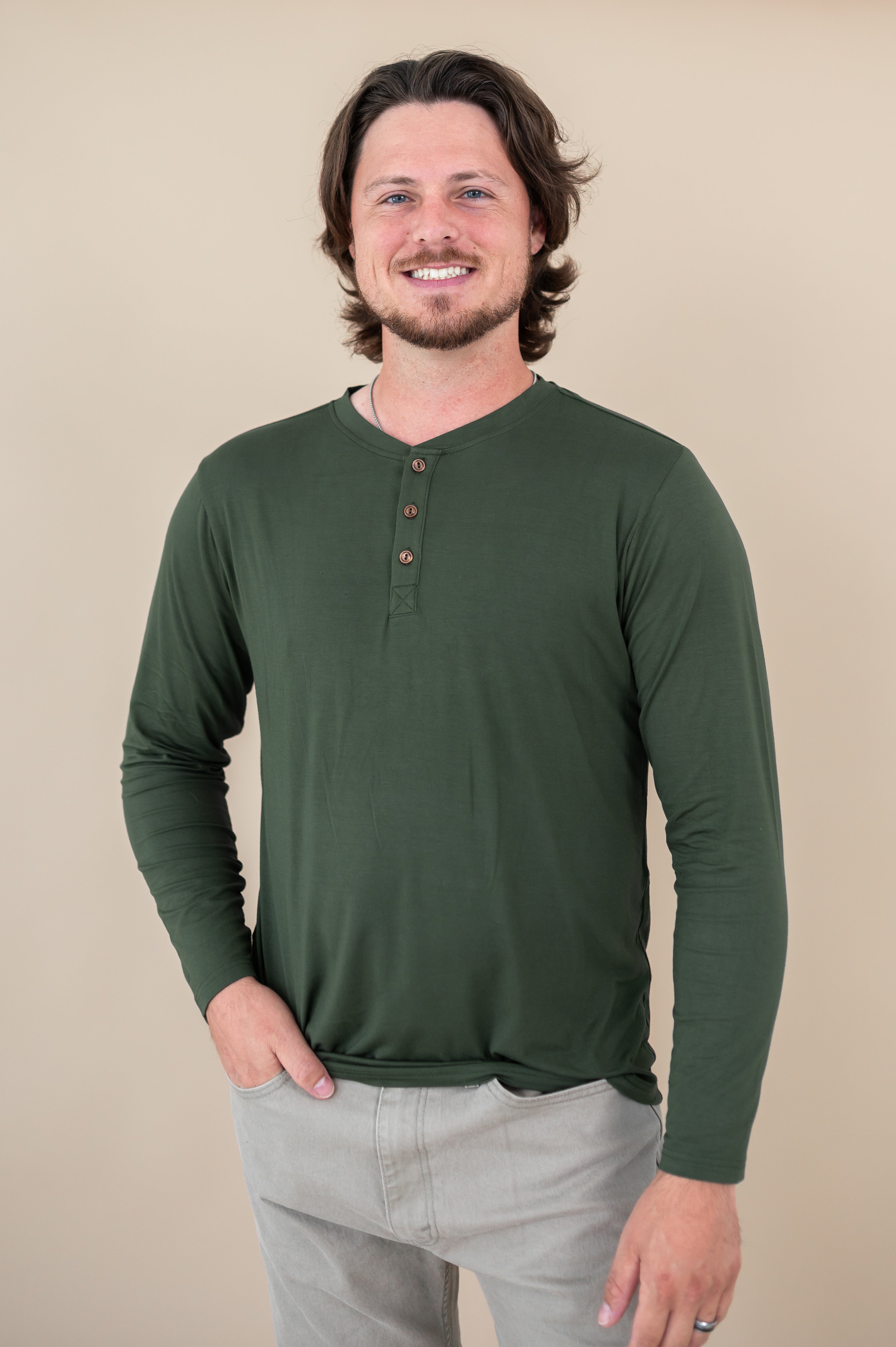Smiling male model wearing the Kyte Men's Long Sleeve Henley Top in Fir