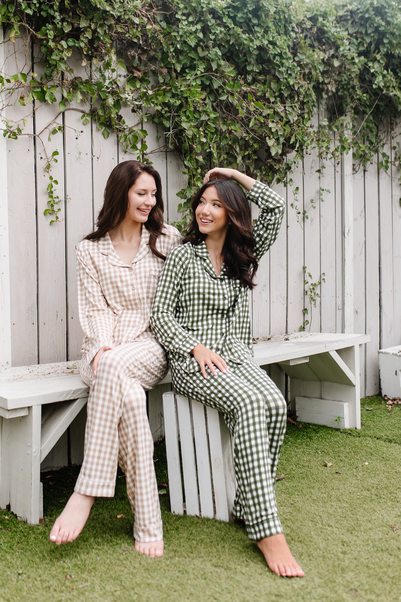 Models sitting on a bench while wearing the Kyte Women's Long Sleeve Pajama in Bisque and Fir Gingham