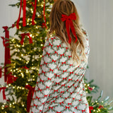 Woman putting a bow on a Christmas tree while modeling the back of the Bamboo Long-Sleeved Women's Pajama Set in Holiday Bow