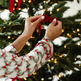 Close up of the arms of the top of the Bamboo Long-Sleeved Women's Pajama Set in Holiday Bow putting a bow in a tree