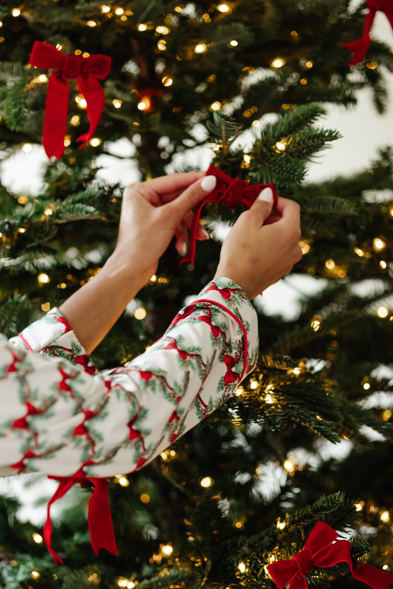 Close up of the arms of the top of the Bamboo Long-Sleeved Women's Pajama Set in Holiday Bow putting a bow in a tree