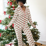 Smiling model standing in front of a Christmas tree wearing the Long Sleeve Women's PJ Set in Holiday Bow