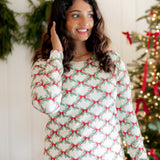 Close up of the top of the Women's Jogger Pajama Set in Holiday Bow shown on a model standing in front of a white paneled wall and decorated Christmas tree