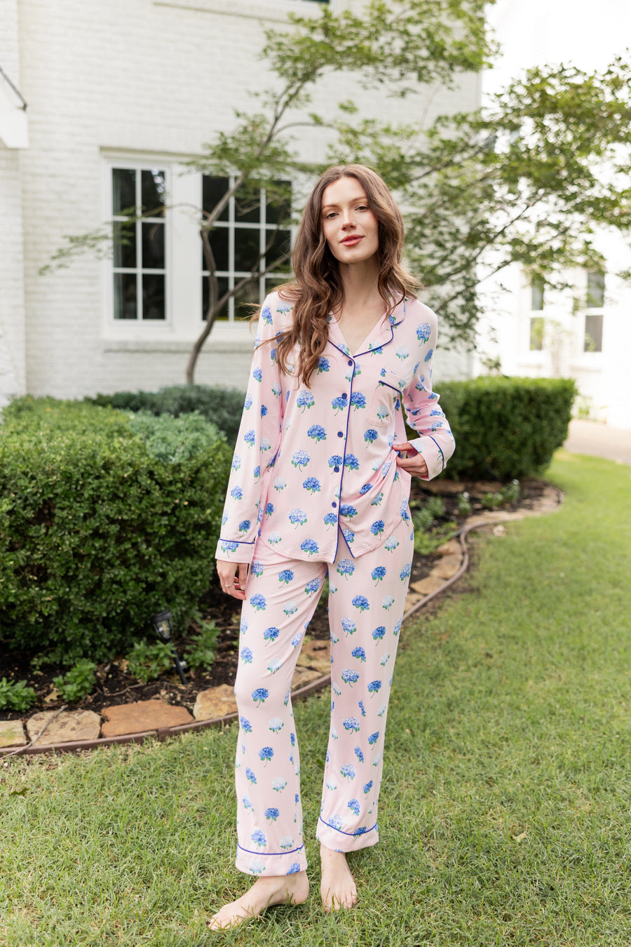 Woman outside with her leg propped and hand on her top in long sleeve pajamas in Hydrangea Sakura print.