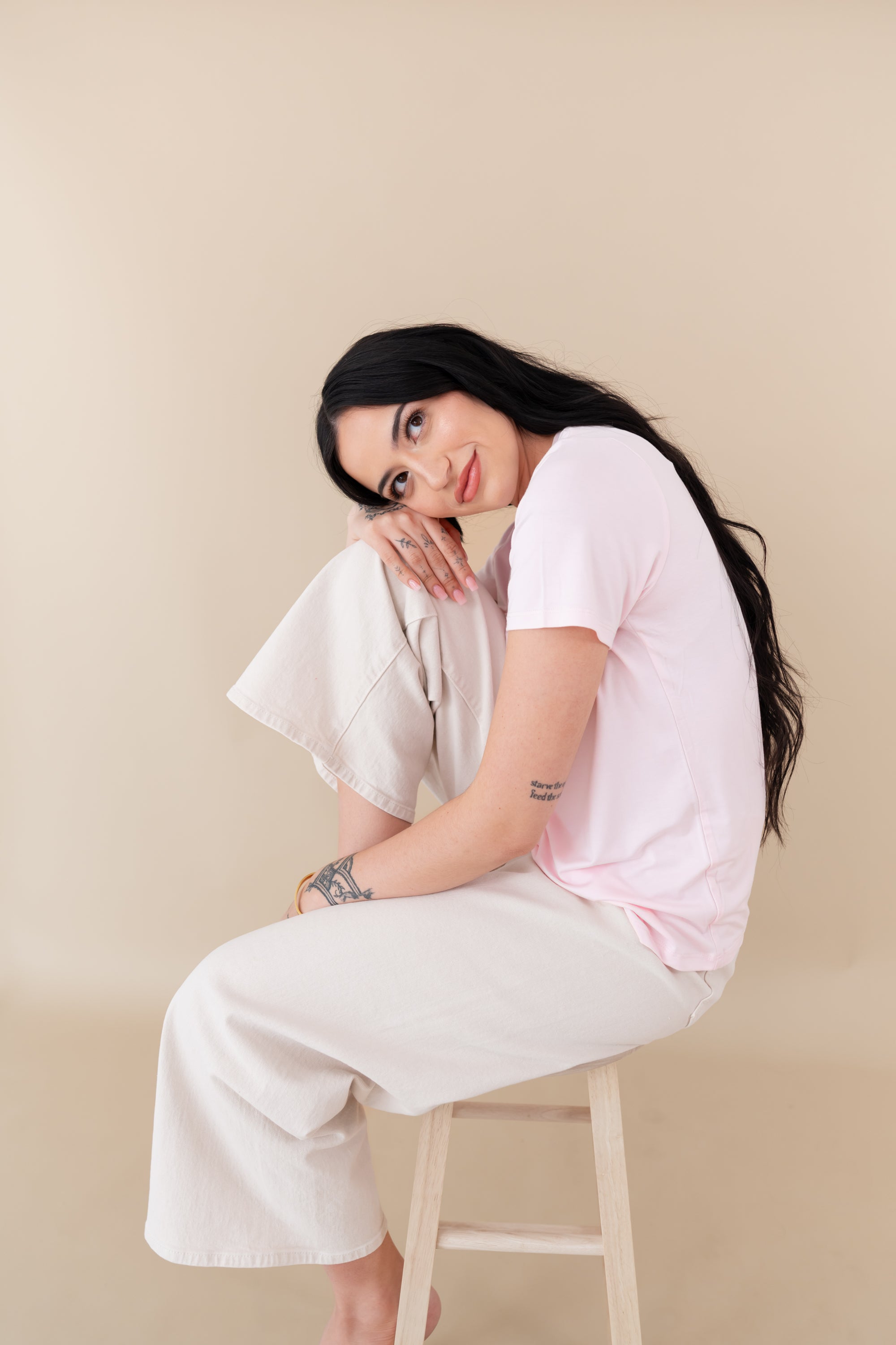 woman sitting on a stool modeling Women's Crew Neck Tee in Sakura