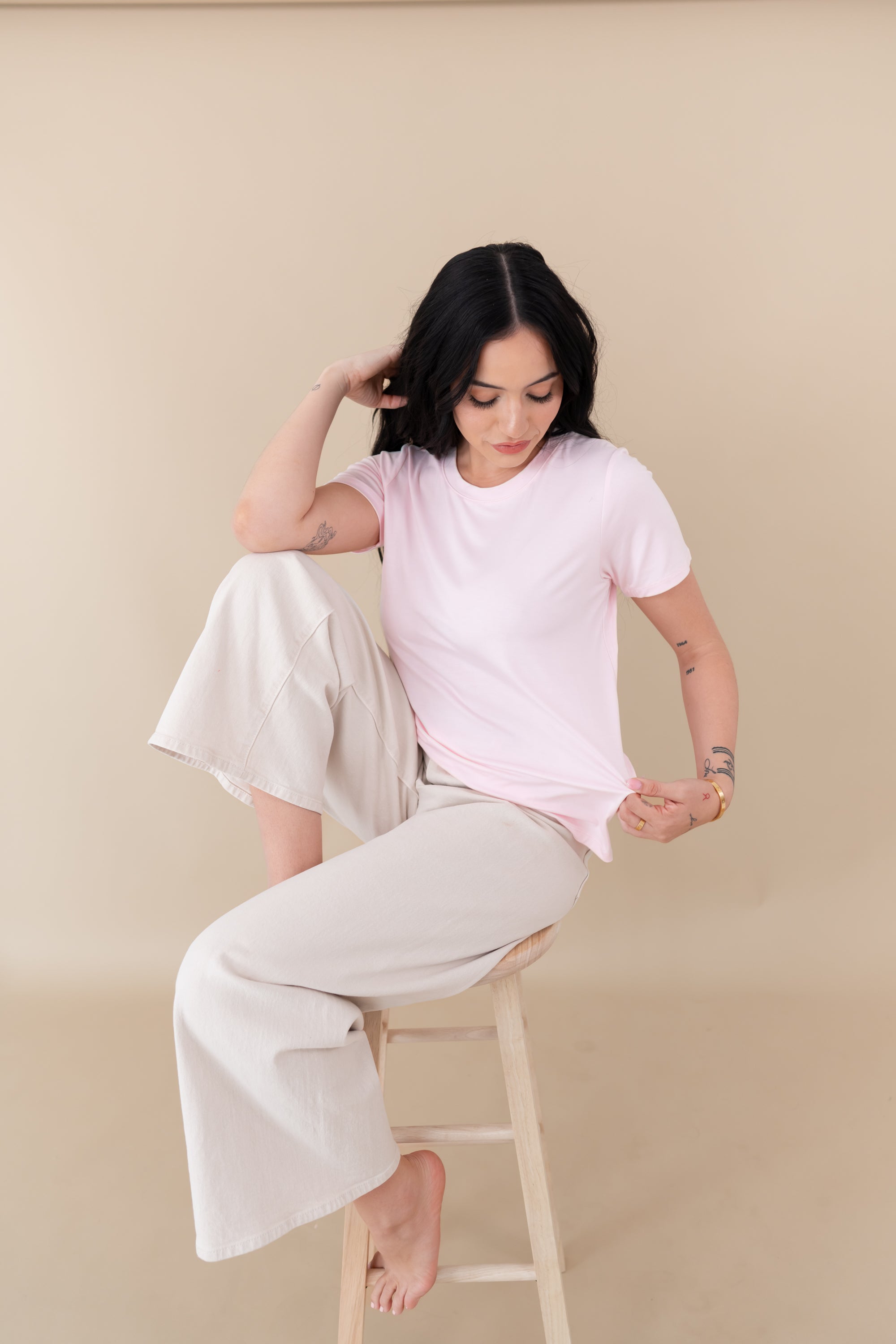 woman sitting on a stool modeling Women's Crew Neck Tee in Sakura