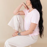 woman sitting on a stool modeling Women's Crew Neck Tee in Sakura