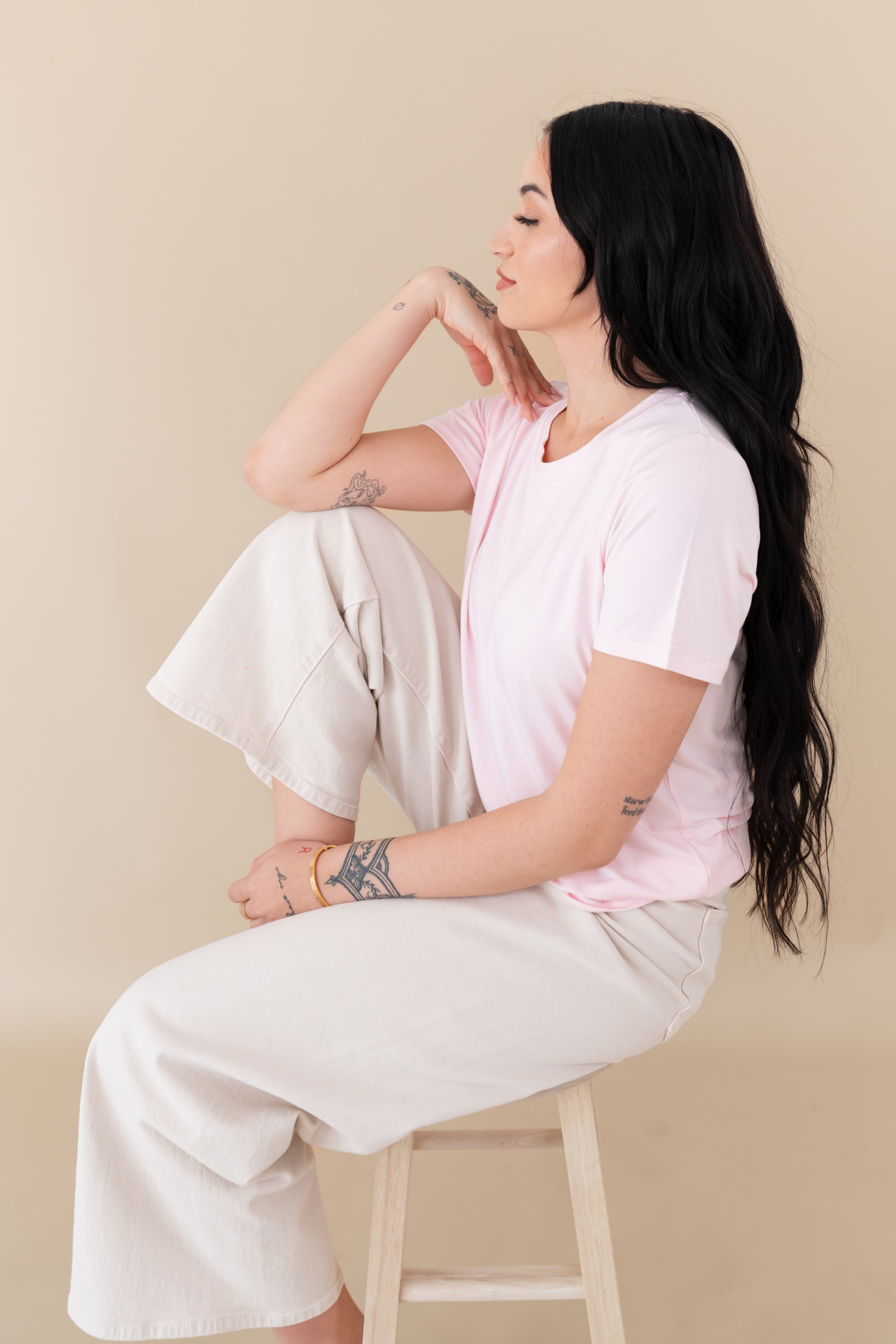 woman sitting on a stool modeling Women's Crew Neck Tee in Sakura