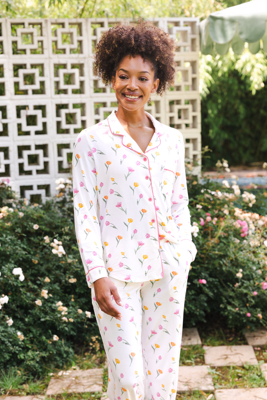 Woman wearing a tulip pajama set standing outdoors with greenery in the background