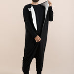 Man wearing a black onesie with a white stripe on a beige background