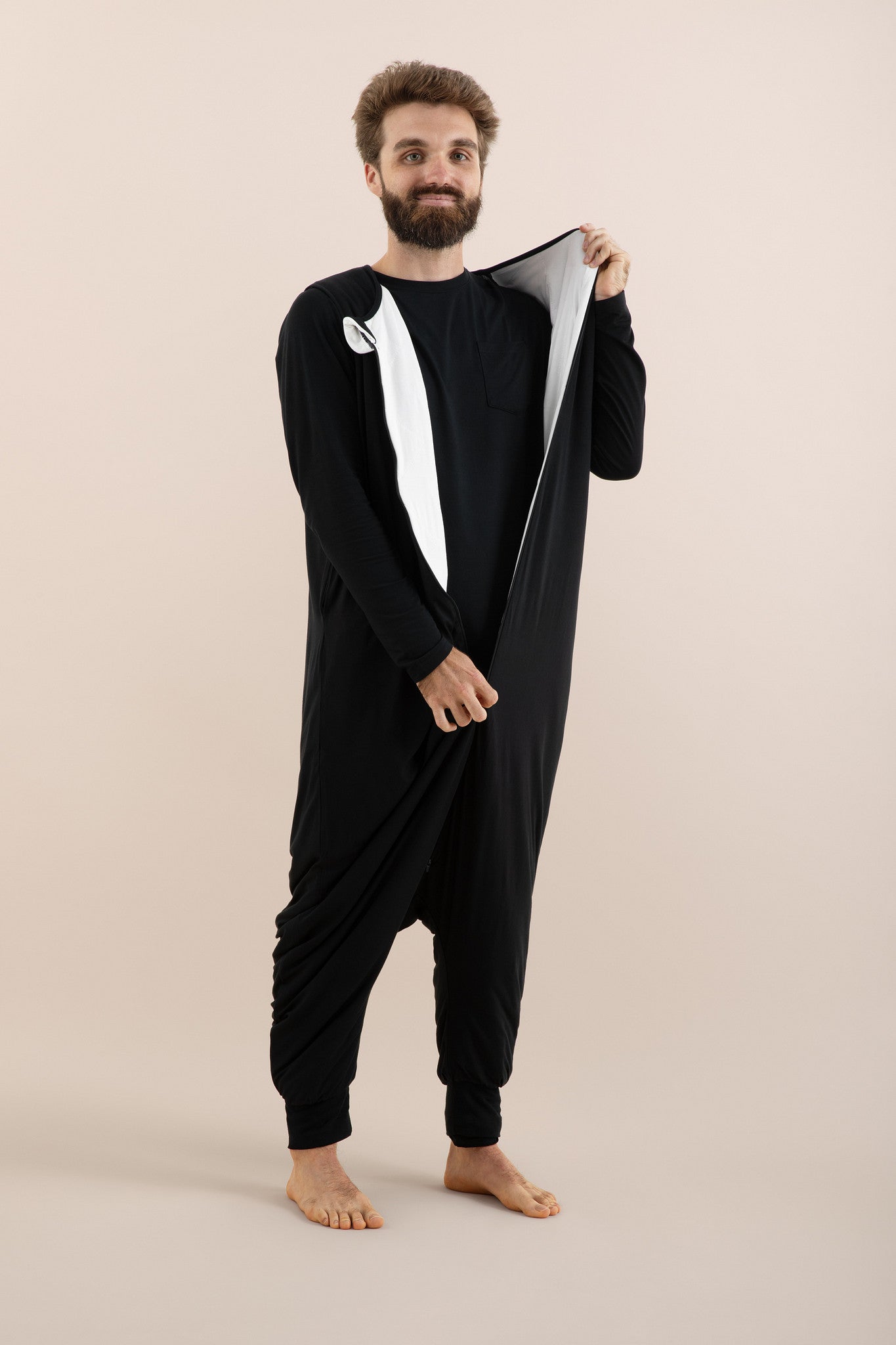 Man wearing a black onesie with a white stripe on a beige background