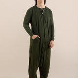Person wearing a green onesie against a beige background