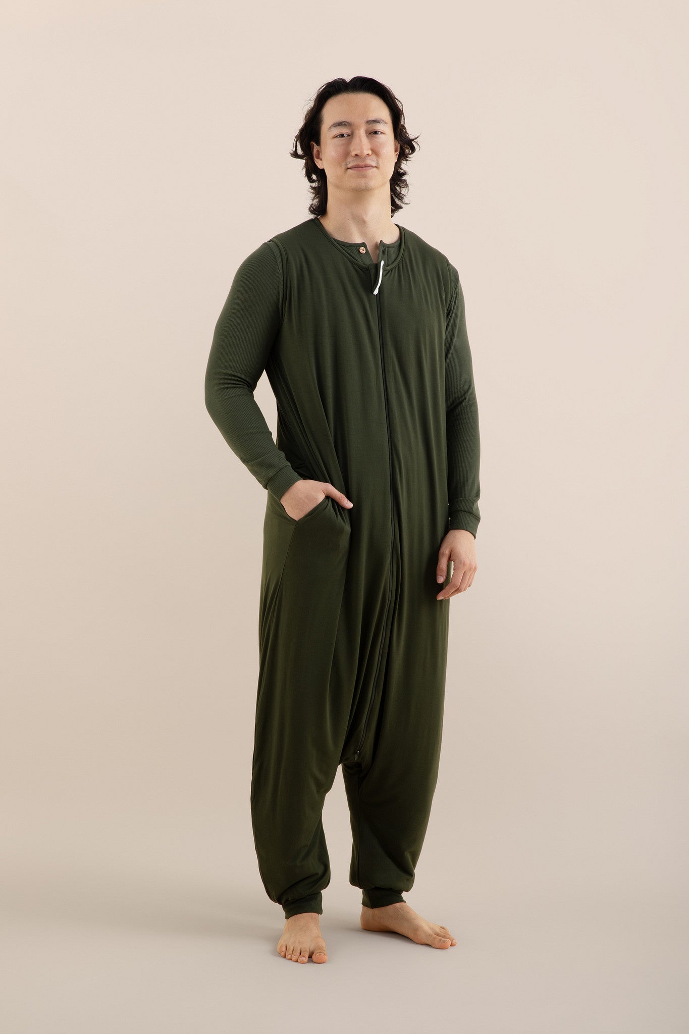 Person wearing a green onesie against a beige background