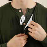 Person wearing a green long-sleeve shirt with buttons, adjusting the collar.