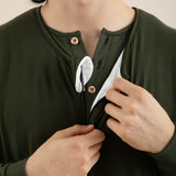 Person wearing a green long-sleeve shirt with buttons, adjusting the collar.