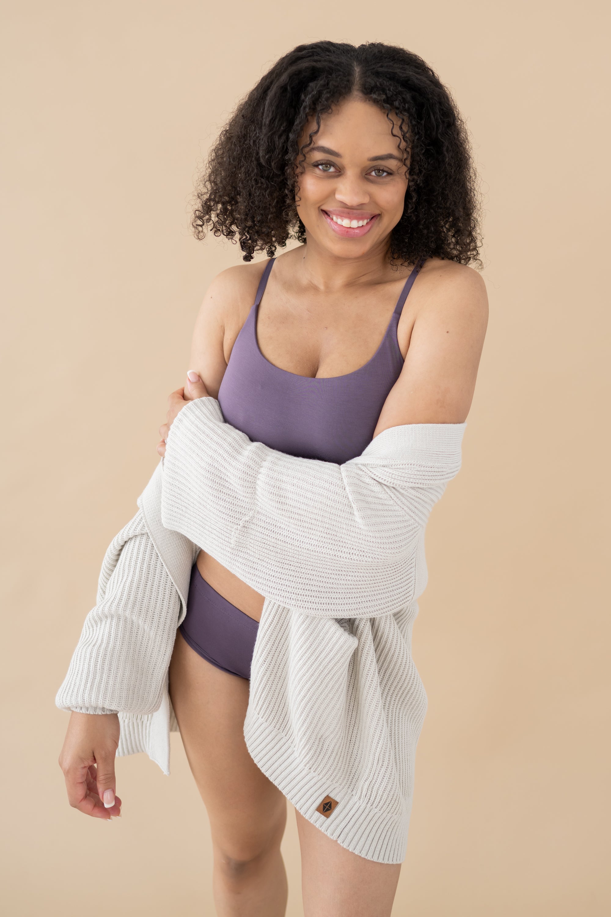 Woman wearing Currant Bralette and Briefs wrapped in Chunky Knit Women's Oversized Cardigan in Oat