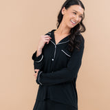Smiling model in Kyte Baby's Women's Long Sleeve Pajama Set in Midnight with Cloud Trim