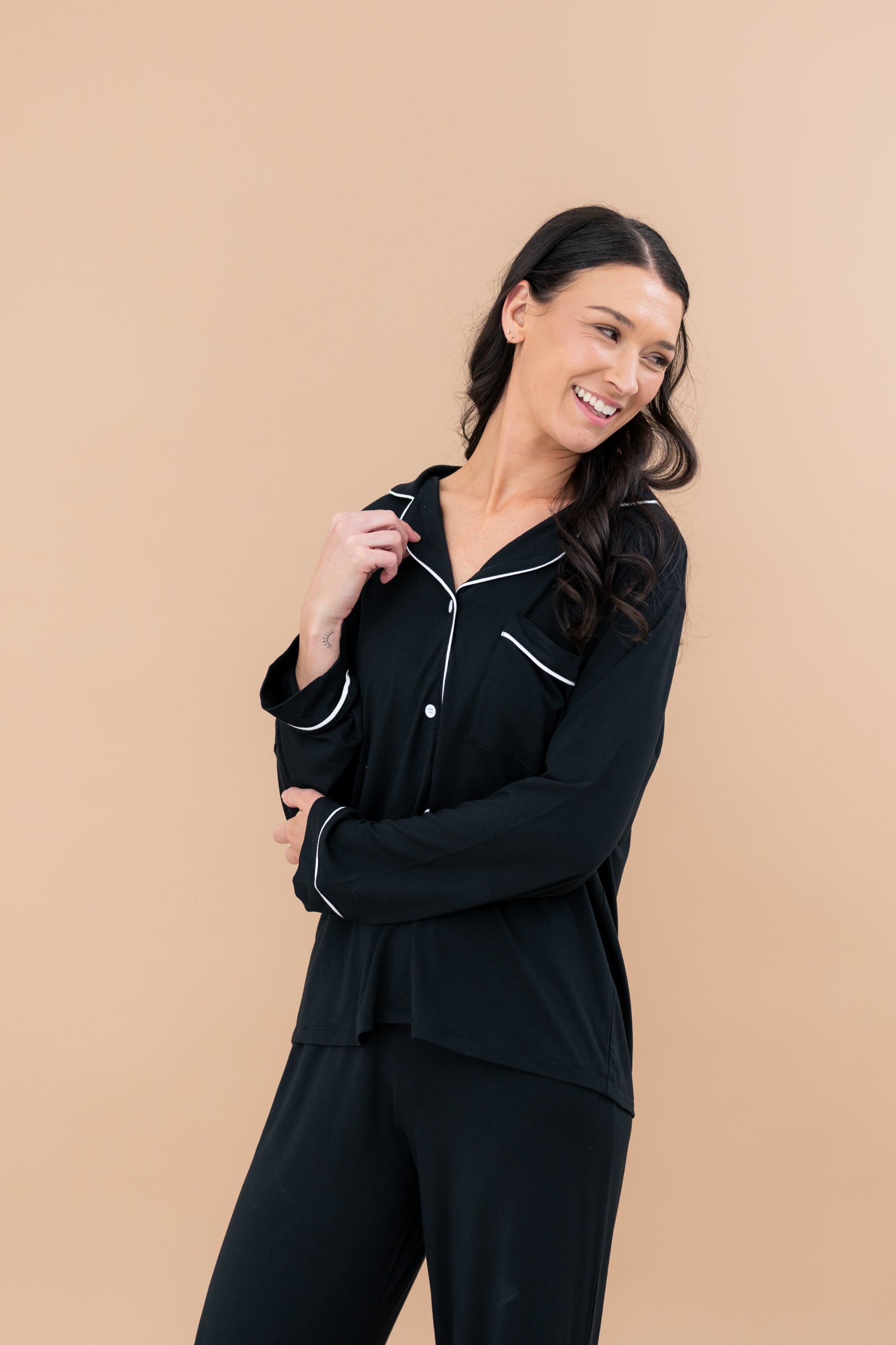 Smiling model in Kyte Baby's Women's Long Sleeve Pajama Set in Midnight with Cloud Trim