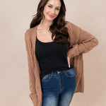 Woman with hand on her hip modeling the Chunky Cable Knit Cardigan in Latte paired with jeans