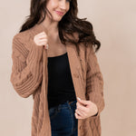 Woman looking to the side while holding on to the Chunky Cable Knit Cardigan in Latte