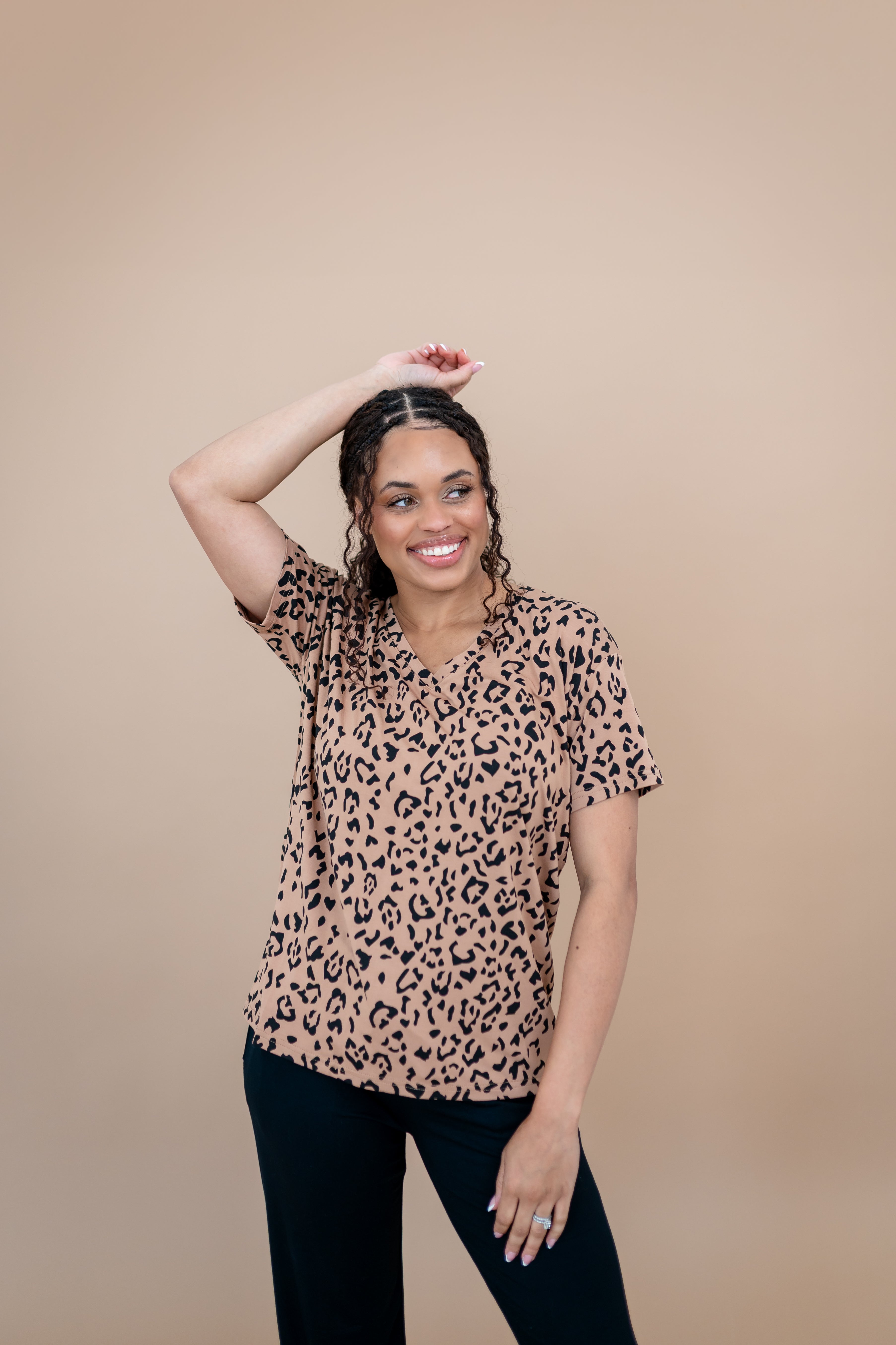 Model with one arm up while wearing the Women's V Neck Tee in Latte Leopard