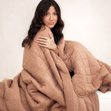 Model wrapped in the Kyte Bamboo Quilt Blanket in Latte 2.5
