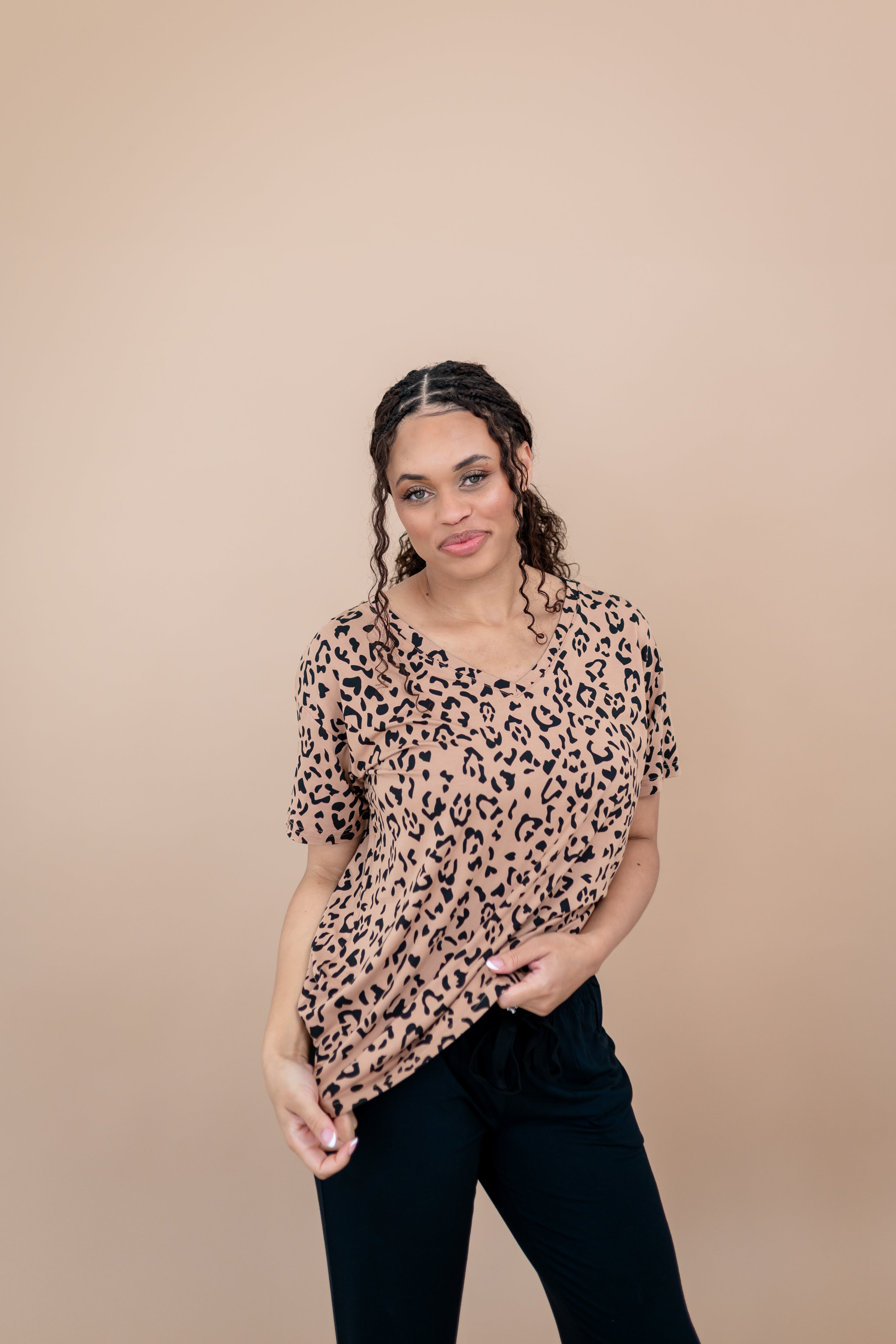 Woman modeling the Women's V Neck Tee in Latte Leopard paired with black pants