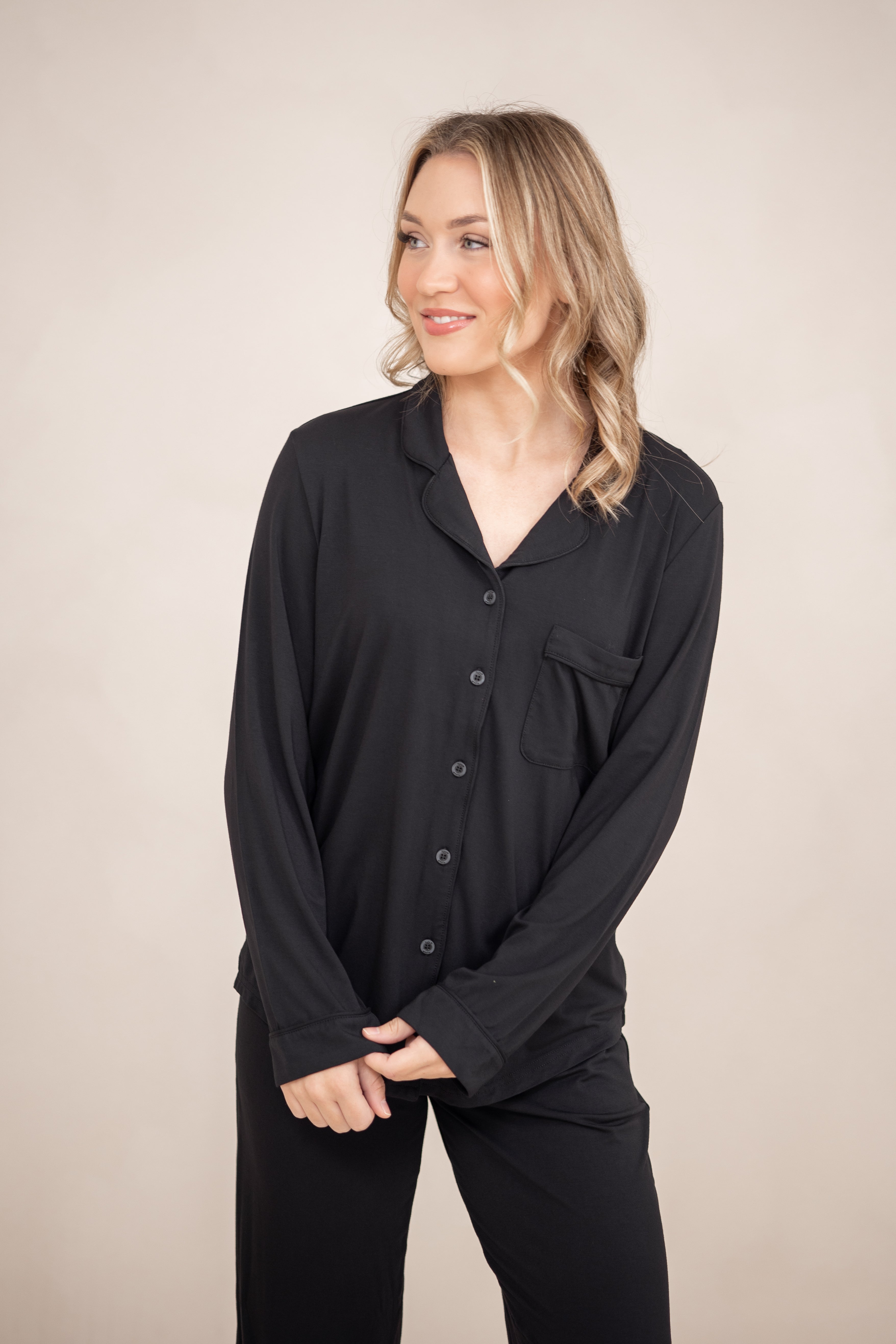 Close up of a female modeling the Long-Sleeved Women's Pajama Set in Midnight with Midnight Trim standing in front of a light neutral background