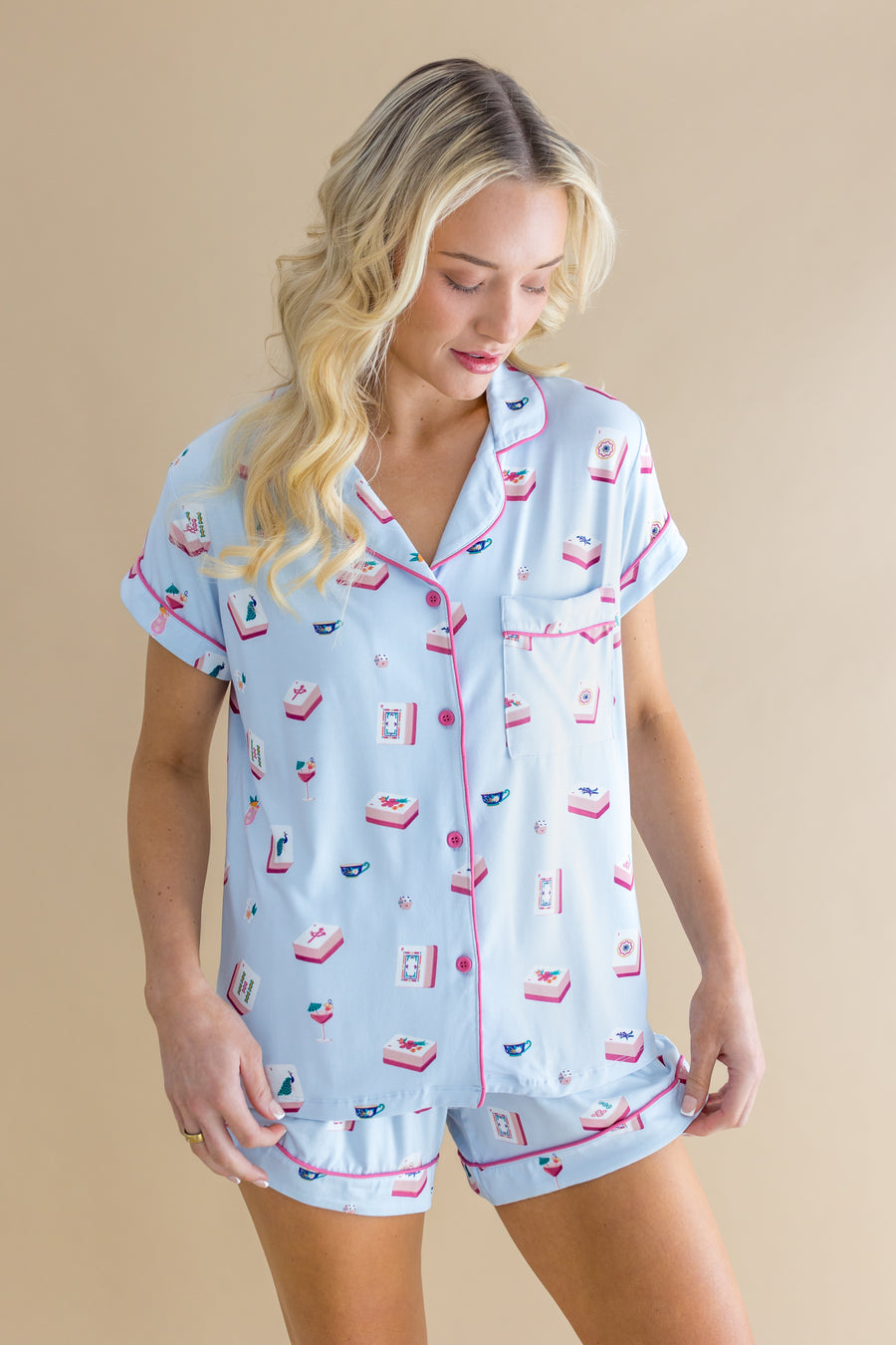 Woman wearing a light blue mahjong pajama set with pink and red Mahjong print on a beige background