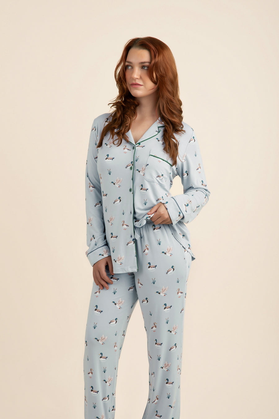 Woman wearing a light blue pajama set with duck pattern on a beige
background