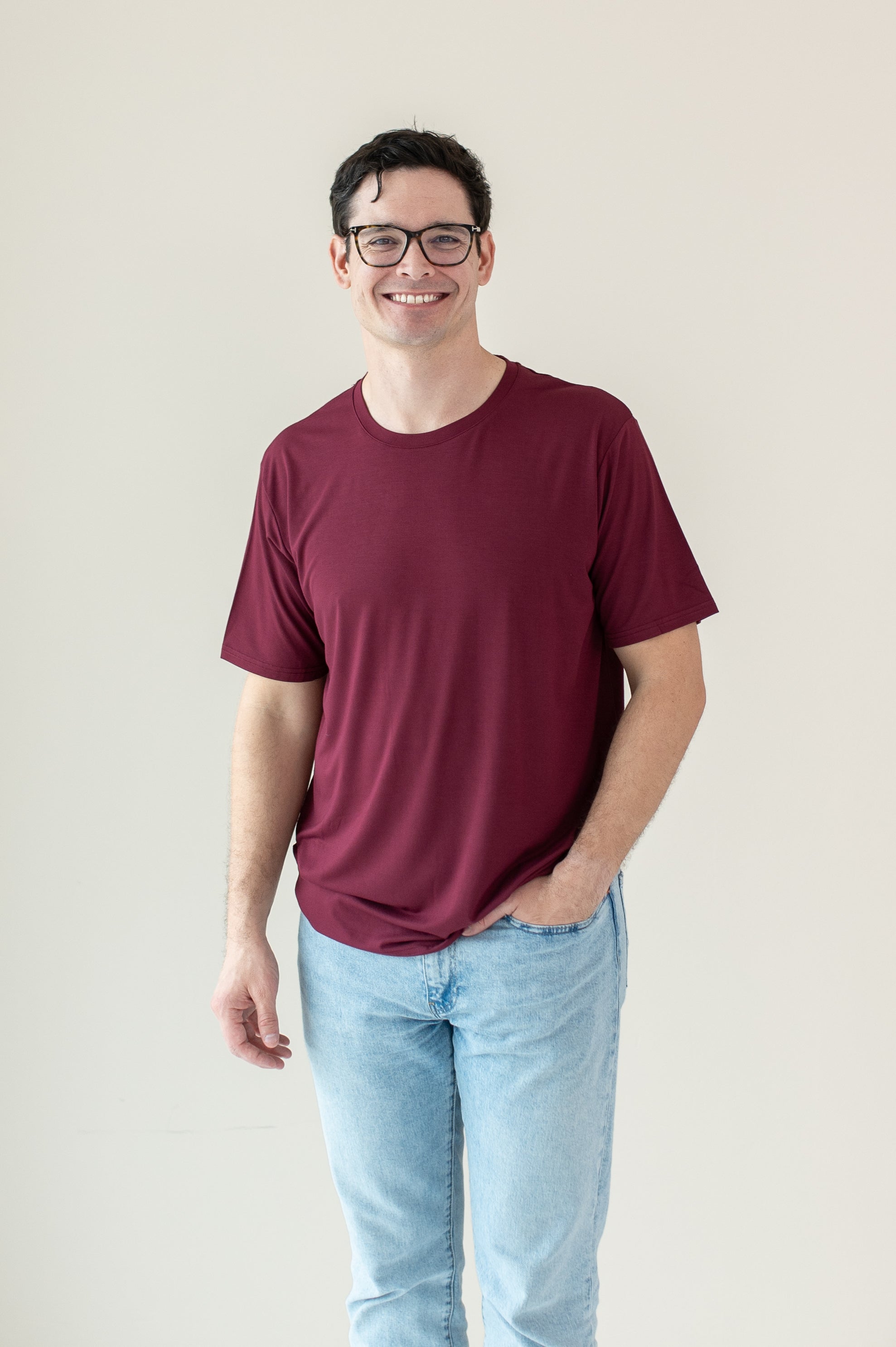 Male model wearing Men's Crew Neck Tee in Burgundy with hand in pocket of light-wash jeans
