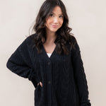 Woman wearing a black cardigan against a plain background