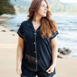 Female model on the beach wearing Kyte Baby's Women's Short Sleeve Pajama Set in Midnight with Cloud Trim