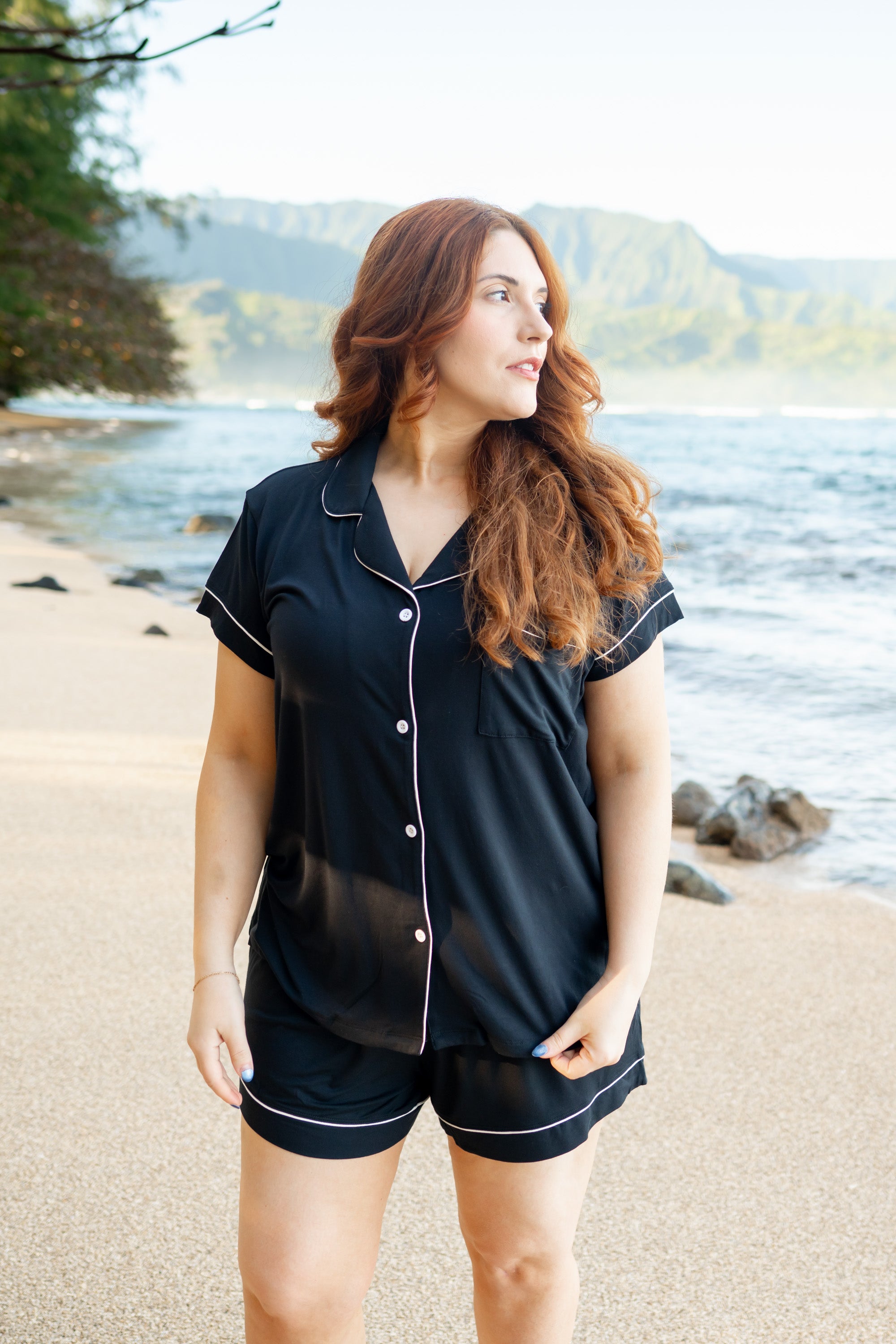 Female model on the beach wearing Kyte Baby's Women's Short Sleeve Pajama Set in Midnight with Cloud Trim