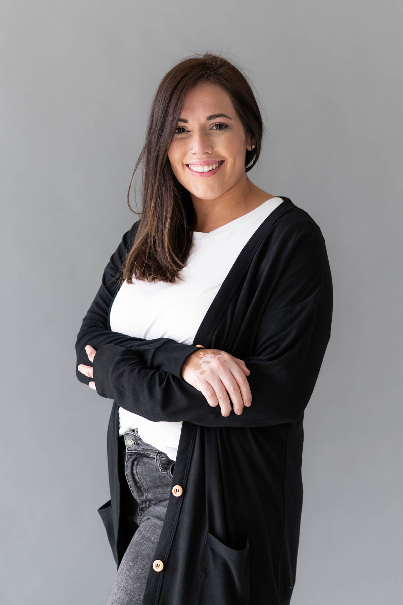 Female model wearing Bamboo Jersey Adult Cardigan in Midnight overtop a white shirt and faded black jeans