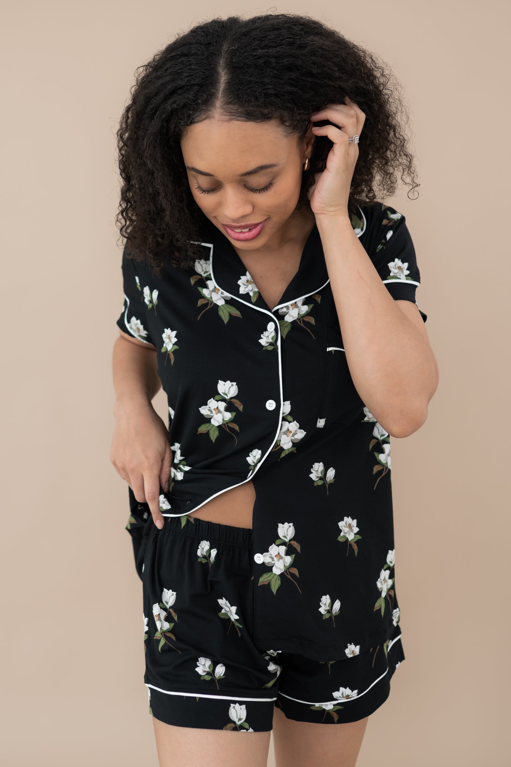 Woman modeling Women’s Short Sleeve Pajama Set in Big Midnight Magnolia with the bottom buttons unbuttoned to show waistband of shorts.