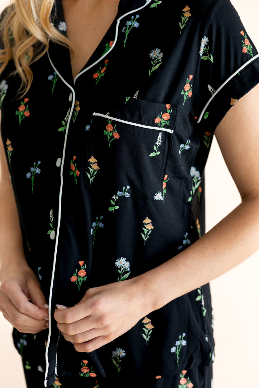 Model showing the front buttons of Women's Short Sleeve Cropped Pajama Set in Midnight Wildflower print on a beige background