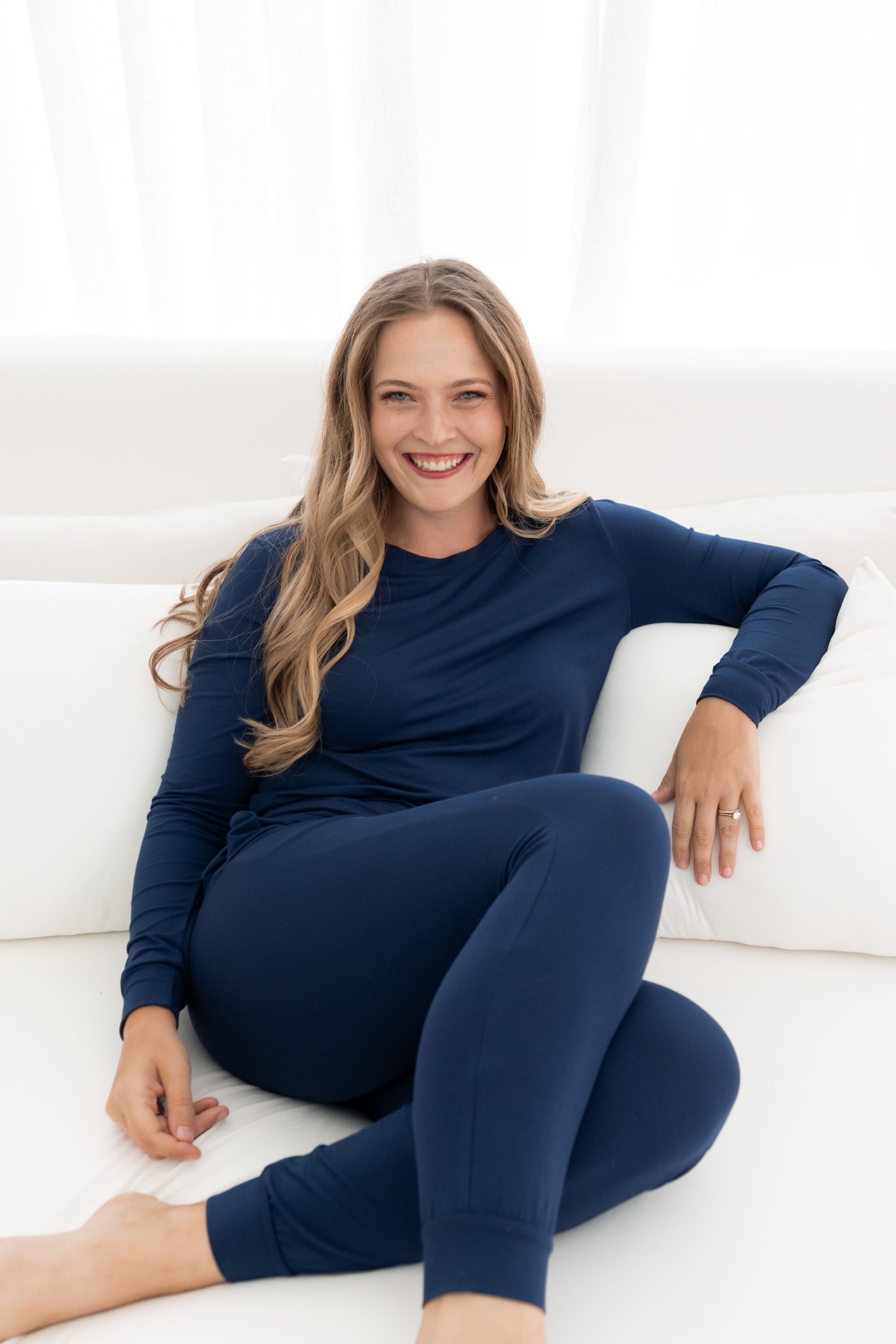Model sitting in bed wearing the Women's Jogger Pajama Set in Navy