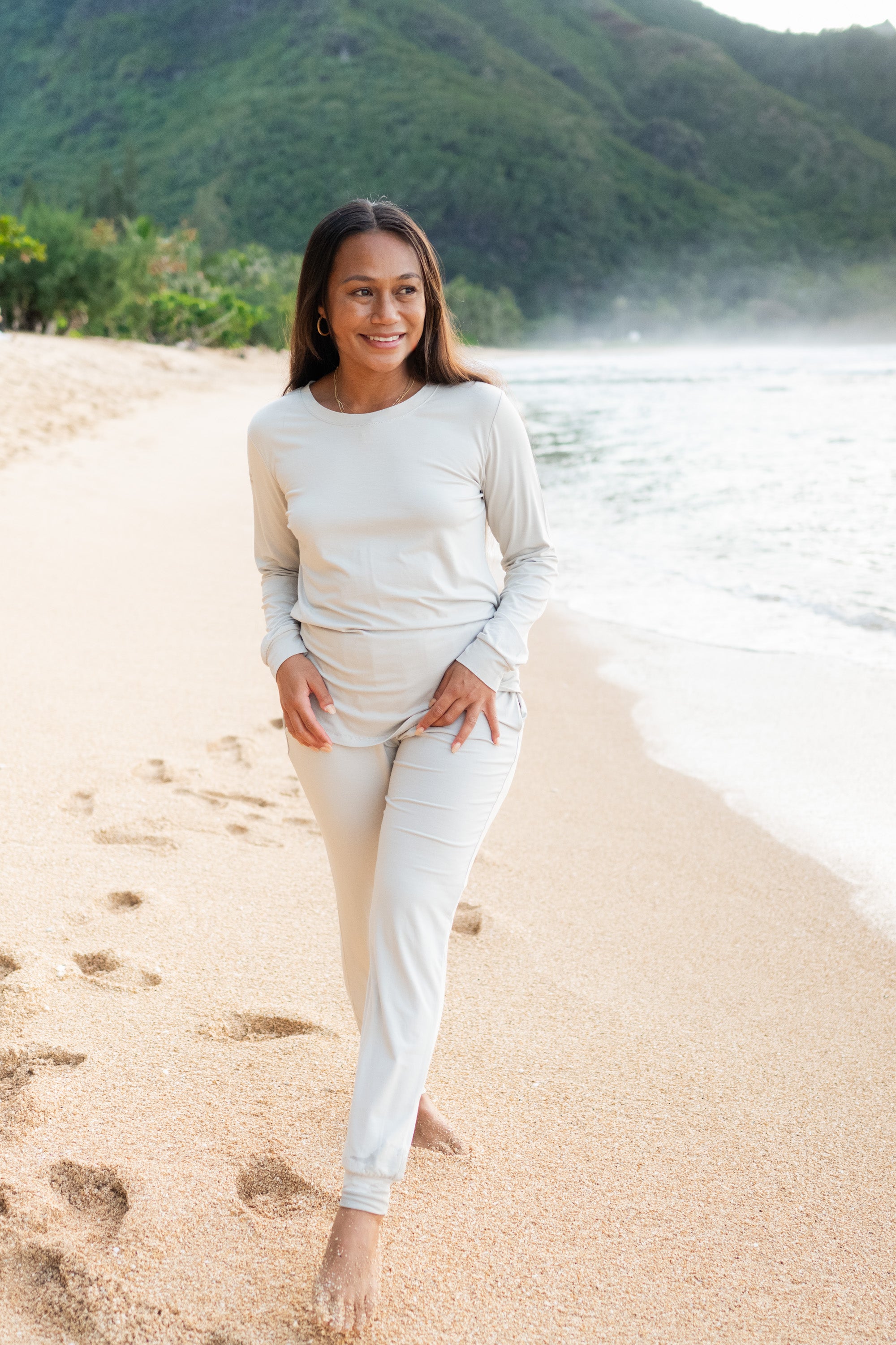 Model walking on the beach wearing the Women's Jogger Pajama Set in Oat