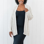 Model wearing the Chunky Cable Knit Cardigan in Oat layered over the Ribbed Cami dress in Midnight