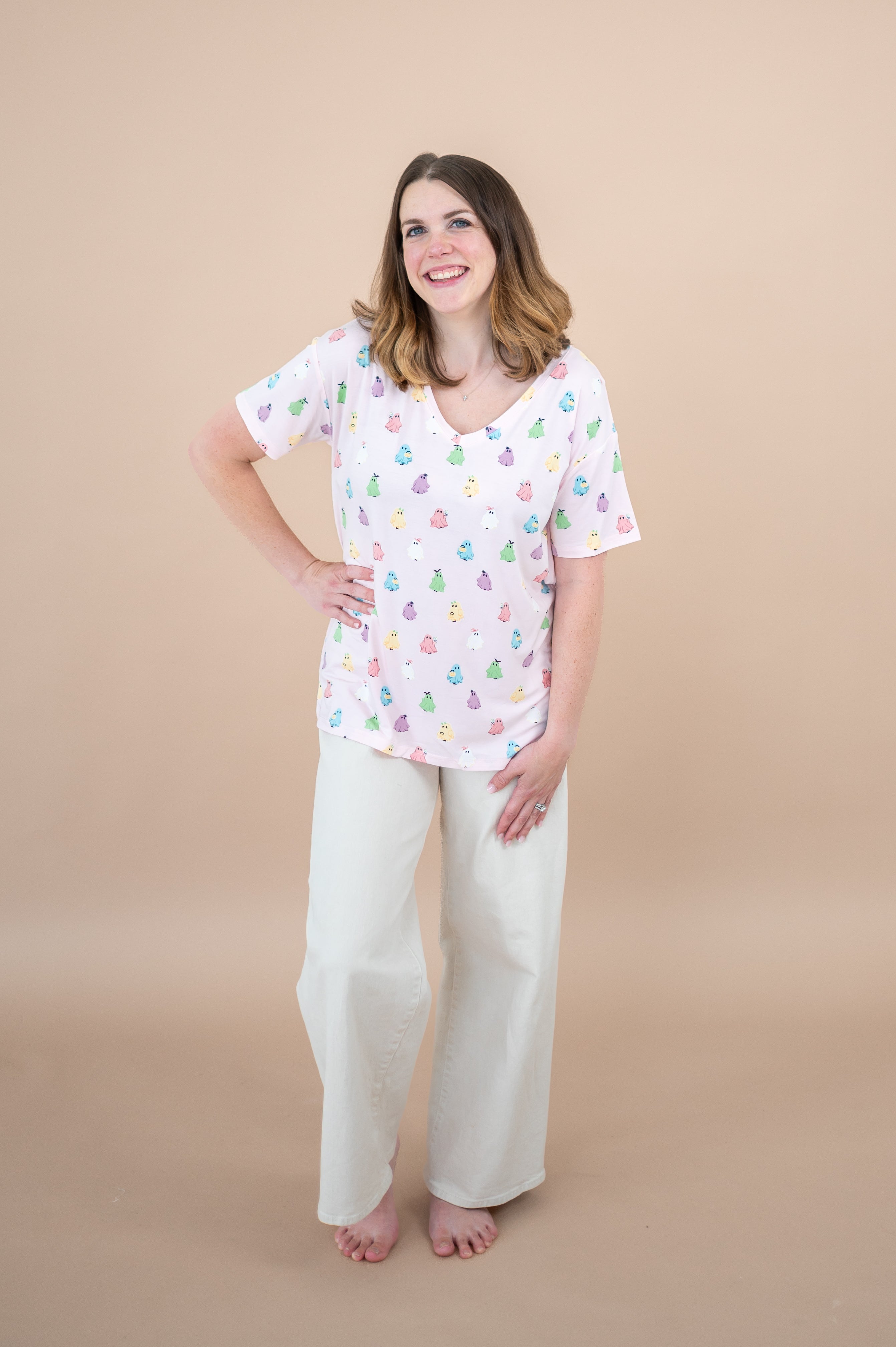 Woman standing with hand on hip while modeling the Women's V Neck in Pastel Ghost paired with Khaki pants