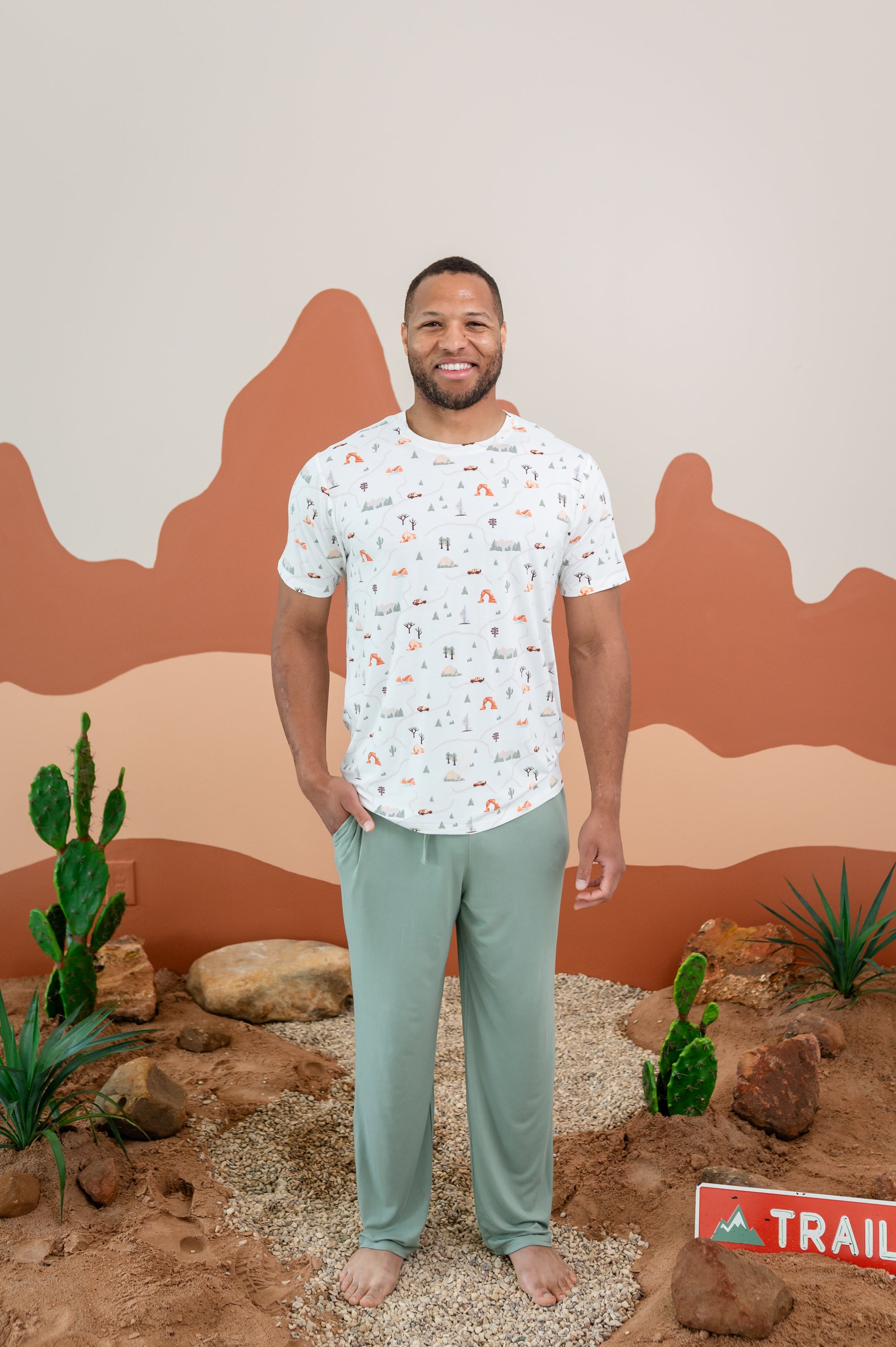 Man modeling Men's Crew Neck Tee in Road Trip and Thyme Lounge Pants with a dessert backdrop