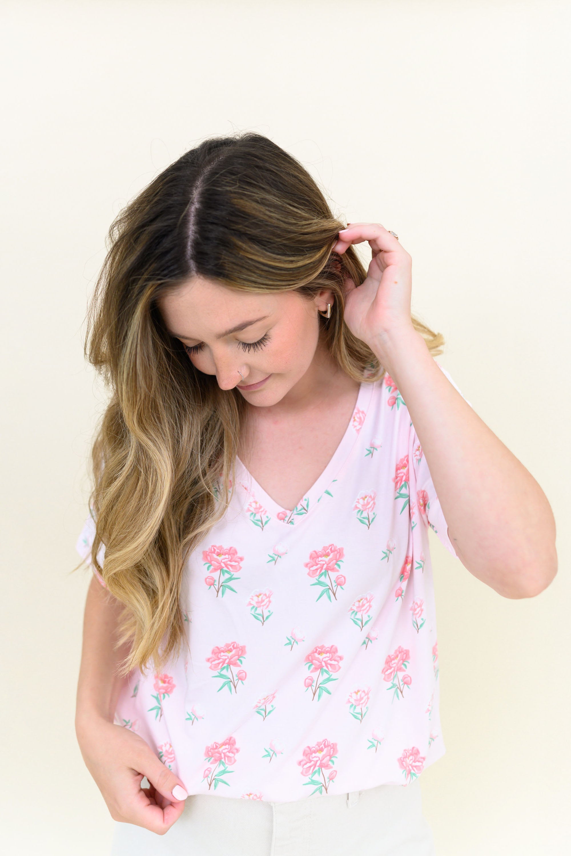 Woman modeling Women's Relaxed Fit V-Neck in Sakura Peony looking down towards tee