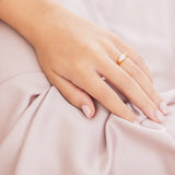 Hand with a ring on a soft pink fabric background