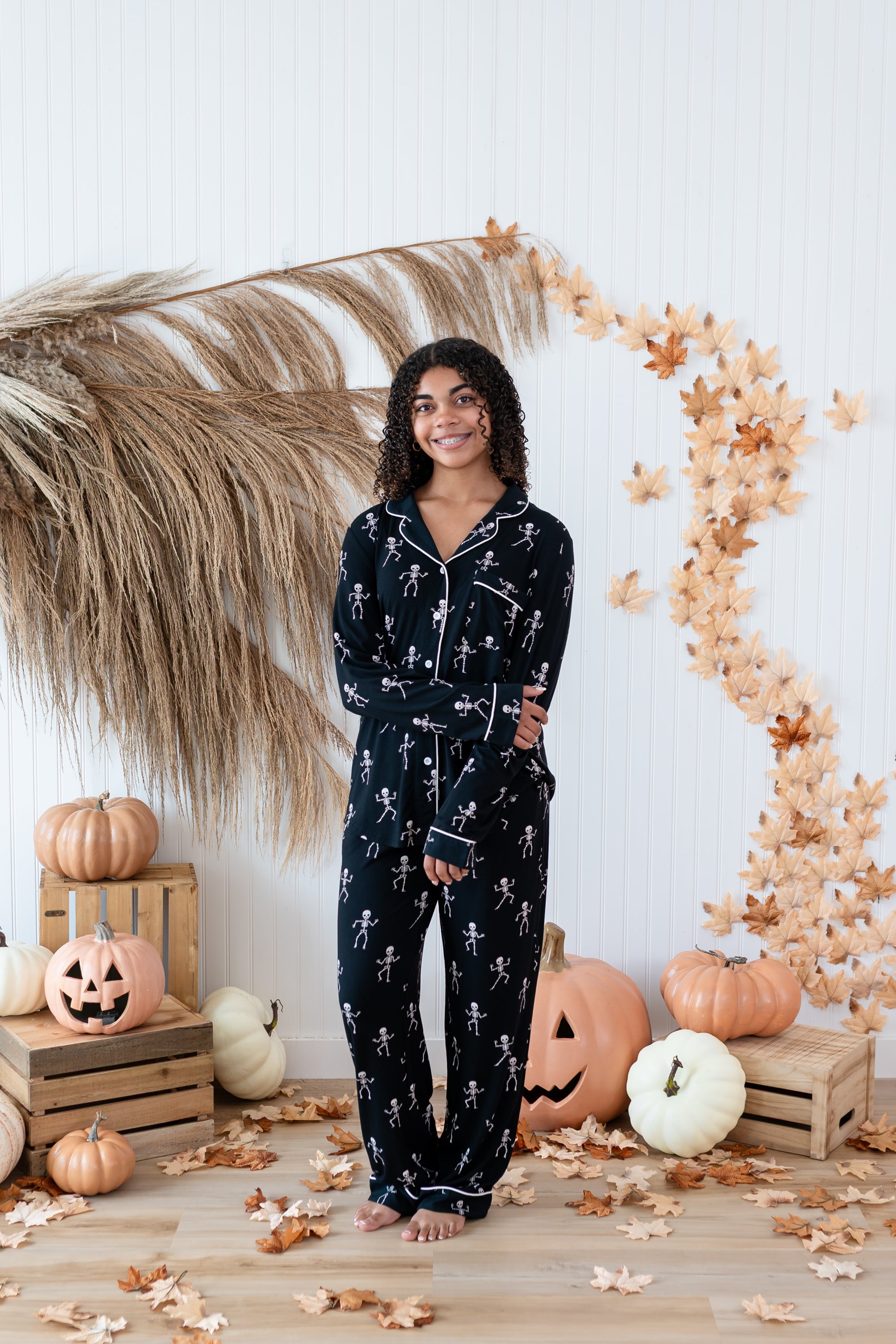 Smiling model in front of a Fall backdrop wearing the Long Sleeve Pajama Set in Skeleton
