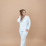 Female model standing with one hand in pants pocket and the other hand in her hair wearing the Long-Sleeved Women's Pajama Set in Small Mist Stripe