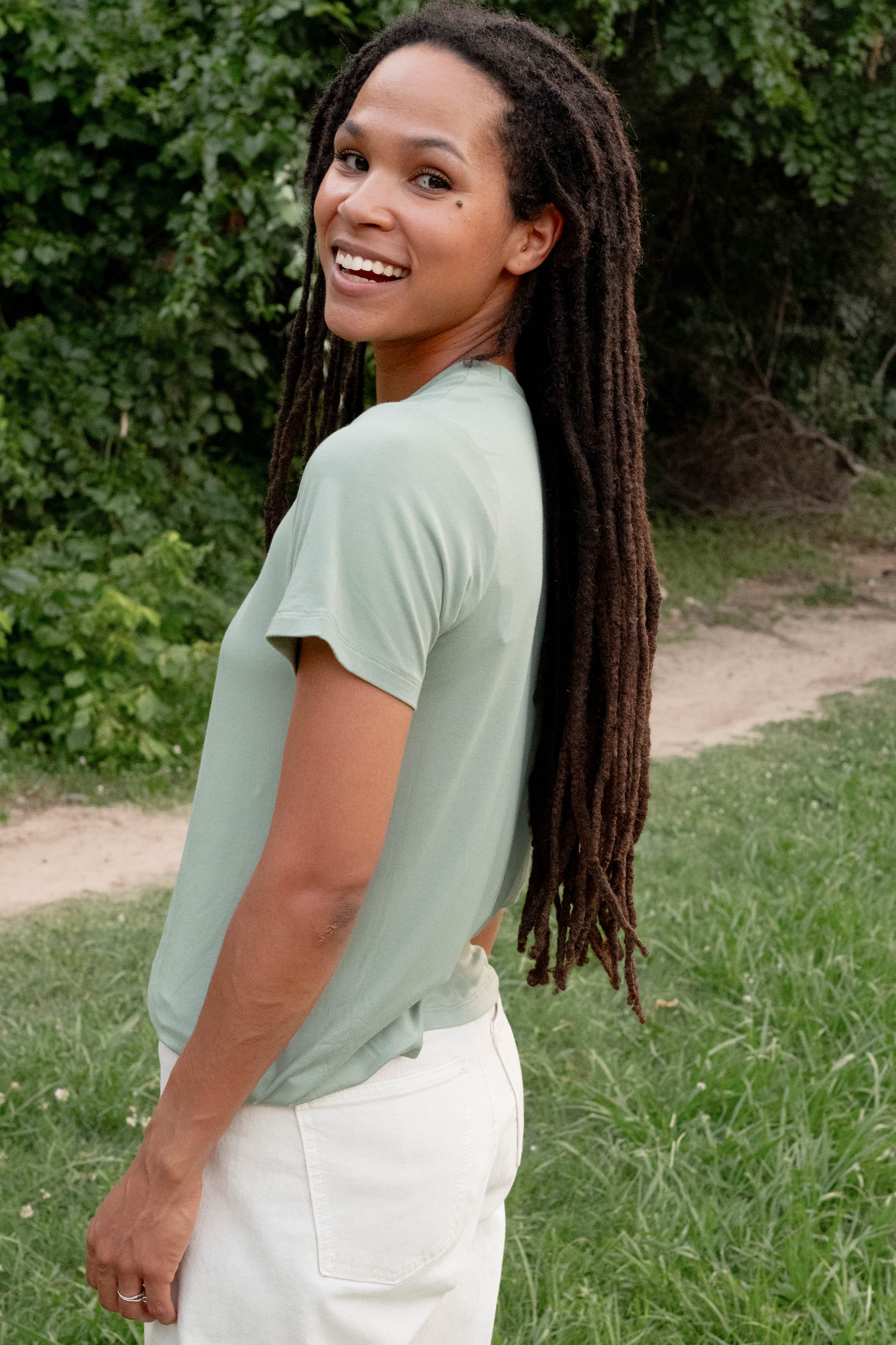 Side view of a female model wearing the Women's Crew Neck Tee in Thyme